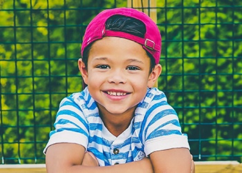 Young boy with backward baseball cap smiling