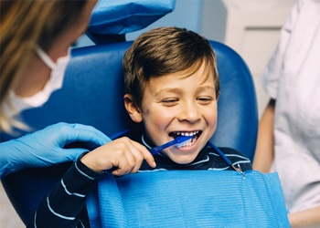 A child brushing his teeth in the dental chair 