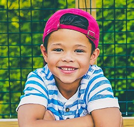 Little boy smiling with backward baseball cap