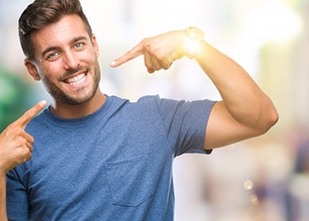 young man pointing to his smile with dental crowns in South Windsor 