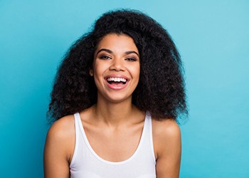 young woman smiling against turquoise background 