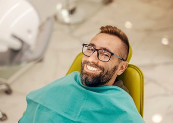 Happy male dental patient reclining in treatment chair