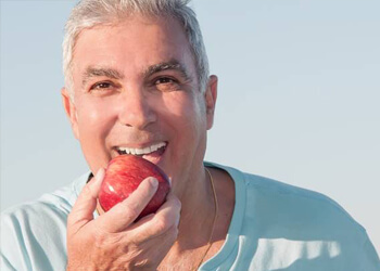 Older man eating a red apple