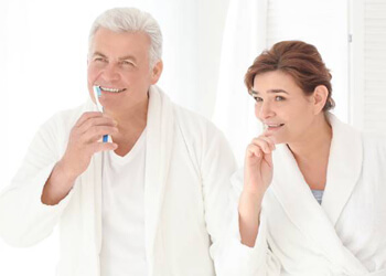 Older man and woman brushing teeth