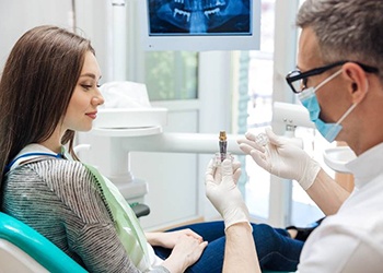 dentist showing a dental implant to a patient