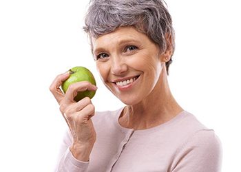 smiling elderly woman holding a green apple