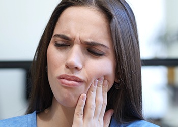 Woman grimacing holding cheek