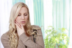 woman holding her jaw in pain