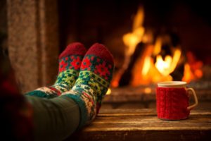 person sitting by a fire with a mug