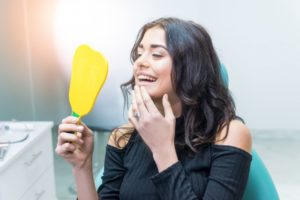 woman admiring her smile after getting dental crown in South Windsor 