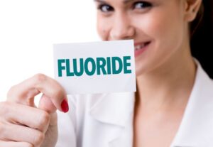 Dental professional holding a card that says, “fluoride” 