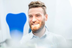 Dental patient looking at himself in hand mirror 